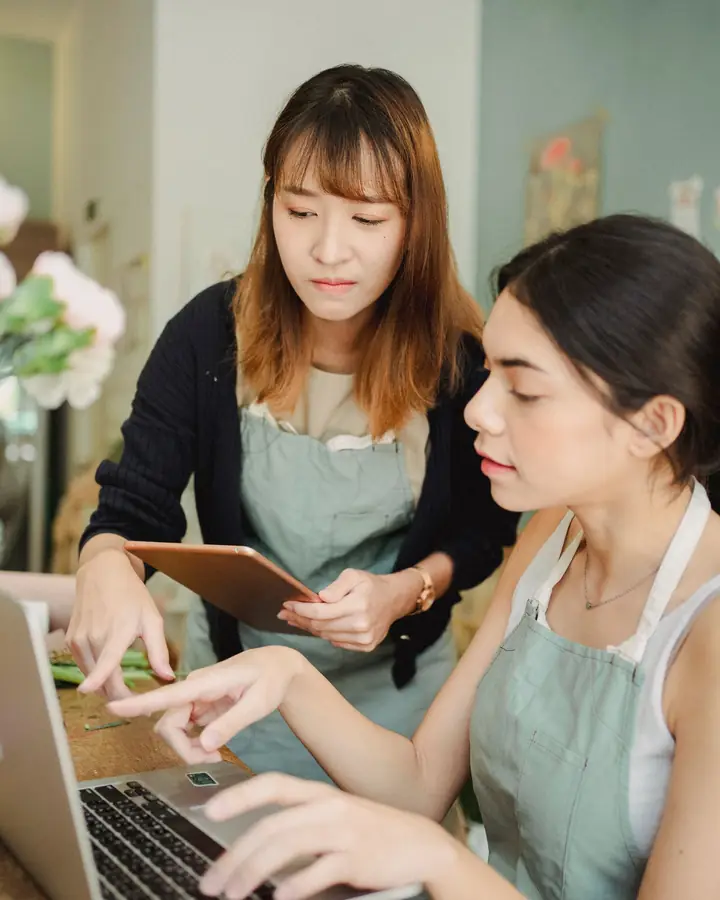 Two shop owners working through orders on a laptop together